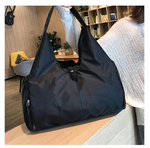 Lifestyle shot of a black large capacity yoga tote bag carried by a model in a modern setting