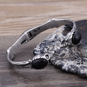 Bracciale teschio argento retrò da uomo con pietre nere su sfondo di legno e roccia