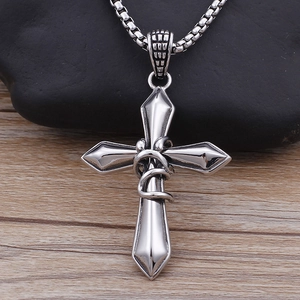 Silver stainless steel cross necklace with snake detail on a rustic dark stone background