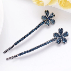 Detail of two dark blue floral hair clips with sparkling crystal rhinestone embellishments