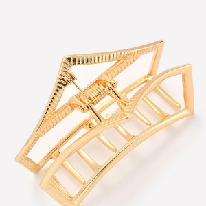 Detail of golden geometric hollow metal hair claw clip with sturdy visible spring