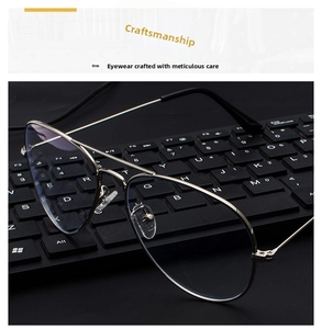 Detail view of silver metal aviator glasses frame resting on a black computer keyboard