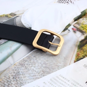 Detailed shot of black leather belt featuring a modern square golden pin buckle