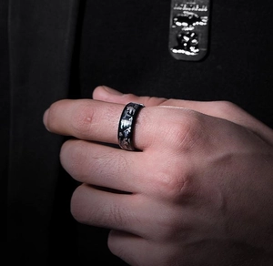 Close-up of men's black titanium ring with silver camouflage pattern on a male hand