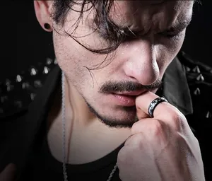 Close-up of men's black camouflage titanium steel ring and matching gothic stud earrings