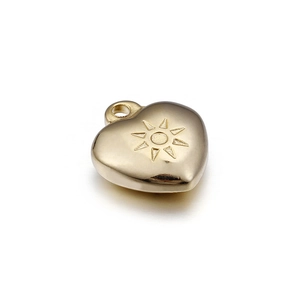 Polished gold heart pendant with sunburst engraving and hanging loop on white background