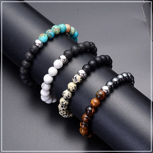Detailed view of 8mm tiger eye and lava stone bead bracelets on a black display stand