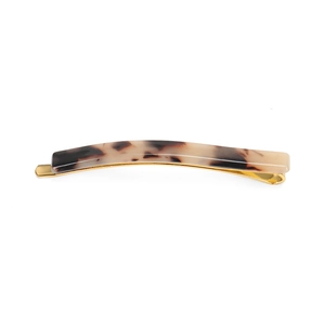 Macro shot of tortoise shell pattern hair clip with gold metal base on white background