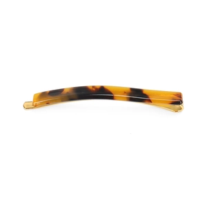 Detailed view of an amber tortoiseshell acetate hair clip with a gold-tone metal base