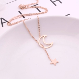 Detail of rose gold moon and star Y-necklace resting on a minimalist white tray