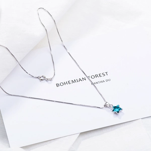 Minimalist silver chain necklace with a deep blue star-shaped crystal pendant