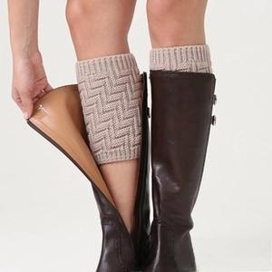 Detail of knitted oatmeal leg warmers featuring herringbone pattern worn with brown leather boots
