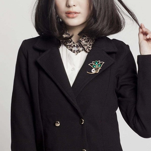 Elegant gold flower brooch with emerald green gemstones and pearls on a black coat