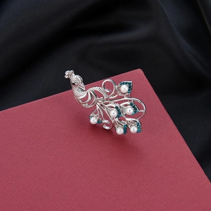 Macro shot of silver peacock brooch featuring white pearls and blue rhinestones on satin
