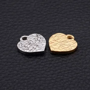 Detailed view of heart-shaped stainless steel charms with hammered texture in gold and silver