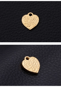 Macro shot of gold stainless steel heart pendant with hammered texture on leather background