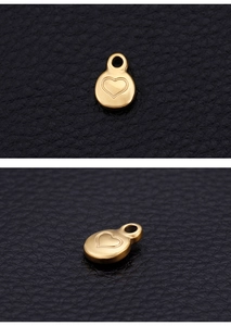 Macro detail of a golden stainless steel round pendant with heart engraving on leather