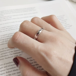 Minimalist S925 sterling silver twisted ring shown on index finger with a vintage book