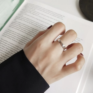 Close-up of a twisted 925 sterling silver Mobius ring worn on a finger with a book background