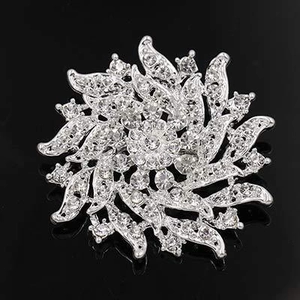 Macro detail of silver floral brooch featuring layered petals and sparkling rhinestones