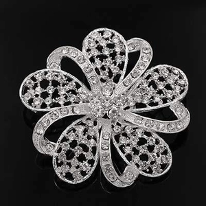 Macro shot of a silver floral rhinestone brooch with hollow mesh petals on a black mirror
