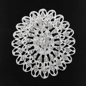 Top view of a silver floral mandala brooch with rhinestones on a black background