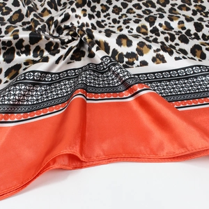Détail d'un foulard en soie à imprimé léopard avec bordures orange et texture lisse