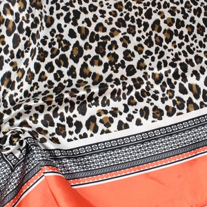 Gros plan détaillé d'un foulard en soie léopard avec bordure orange et texture satinée