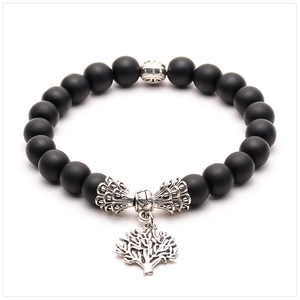 Macro detail of black matte lava stone bracelet with vintage silver tree of life charm