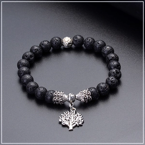Detailed shot of black lava rock beads and silver tree of life charm on an elastic bracelet