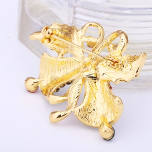 Macro view of gold-plated Christmas tree brooch showing brushed metal texture and safety pin