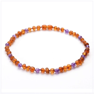 Close-up of Baltic amber and purple crystal beaded baby necklace on a white background