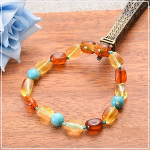 Detail of Baltic amber and turquoise beaded baby bracelet on rustic wood background