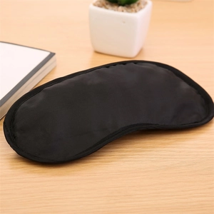 Detailed close-up of smooth black silk sleep mask on a minimalist wooden surface