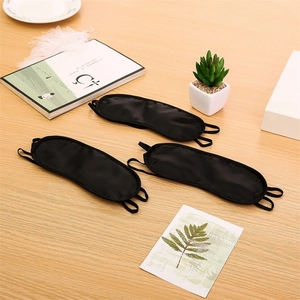 Three-piece set of breathable black silk sleep eye masks on a cozy wooden desk setup