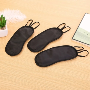 Three-piece set of breathable black sleep masks in smooth faux silk on a wooden table