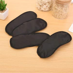 Close-up of four black blackout sleep masks with silky texture on wooden background