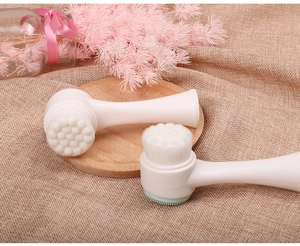 Manual facial cleansing brush with dual-sided silicone bristles on a wooden coaster