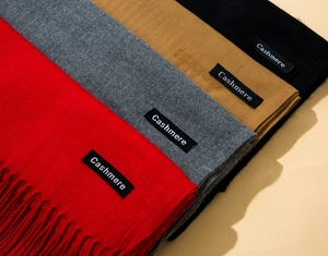 Detail of cashmere scarves in red, grey, camel and black with fringe textures