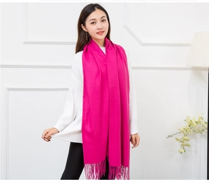 Detail of rose red cashmere feel knit shawl with long fringe tassels on a model