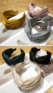Detailed view of knotted velvet headbands in various colors on a rustic wood background