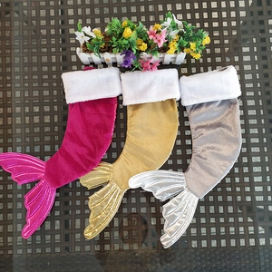 Three sequined mermaid tail Christmas stockings in pink, gold and silver on table