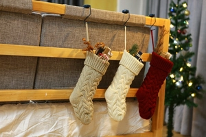 Close-up of knit Christmas stockings in red, cream, and khaki on a bed frame
