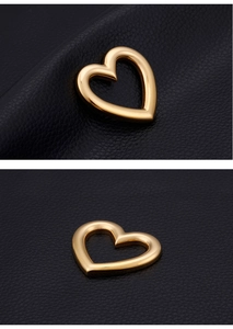 Macro shot of polished gold heart pendant on black textured leather background