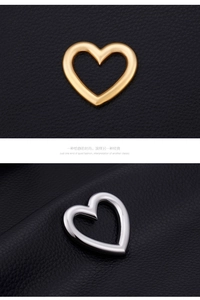 Polished hollow heart charms in gold and silver finish on black leather texture