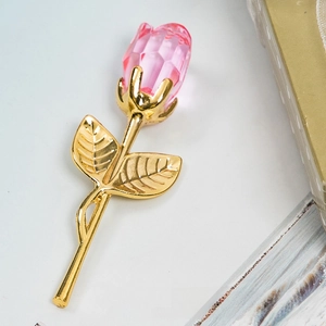 Macro view of crystal rose sculpture with pink petals and gold metal stem and leaves