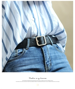 Close-up of minimalist black leather belt with gold square buckle on blue jeans