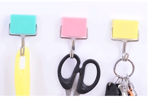 Three colorful magnetic hooks in green, pink, and yellow holding scissors and keys