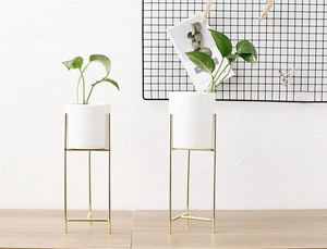 Dettaglio di vasi per fiori minimalisti in ceramica bianca con supporti in metallo dorato