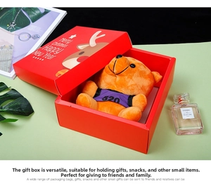 Close-up of red Christmas gift box with cute reindeer and a small orange plush teddy bear